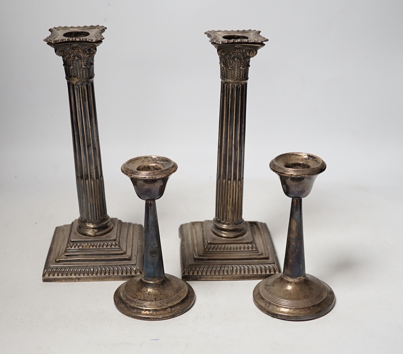 A pair of late Victorian silver Corinthian column candlesticks, Hawksworth, Eyre & Co, Sheffield 1896, 22.5cm, weighted (a.f.), and a smaller pair of silver mounted candlesticks.